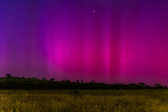 Aurora Australis display lights up the predawn sky in pinks