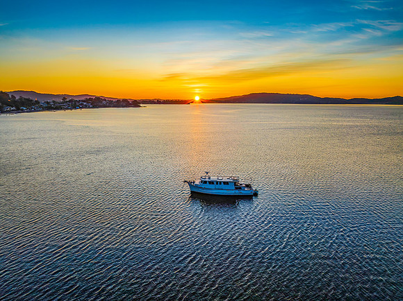 Aerial sunrise waterscape with boat and high cloud