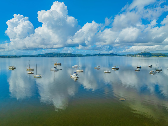 Aerial views over the bay with clouds, reflections and boats