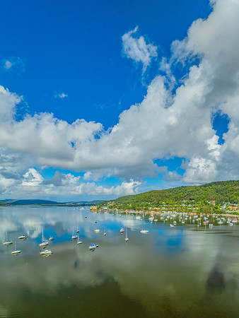Aerial views over the bay with clouds, reflections and boats