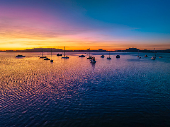 Aerial sunrise waterscape with boats and high cloud