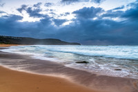 Sunrise at the seaside with rocks and rain clouds