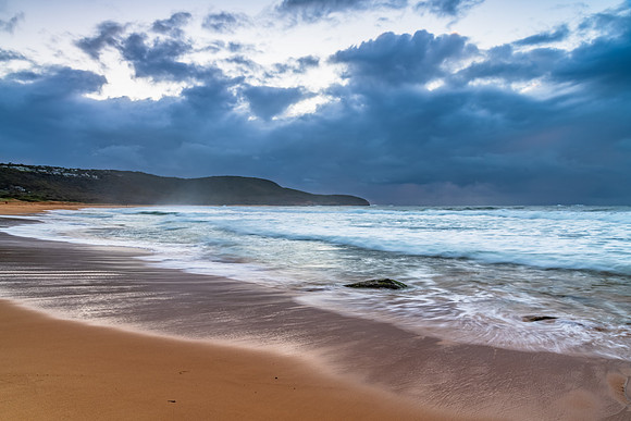 Sunrise at the seaside with rocks and rain clouds