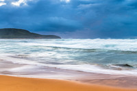 Sunrise at the seaside with rocks and rain clouds
