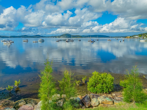 Aerial views over the bay with clouds, reflections and boats
