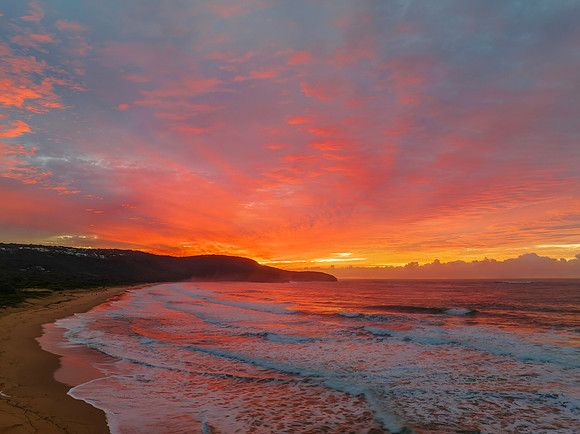 Cloud covered sunrise at the seaside in pink and blue