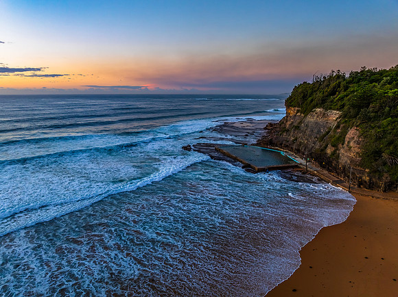 Sunrise at the beach with waves and a smattering of clouds