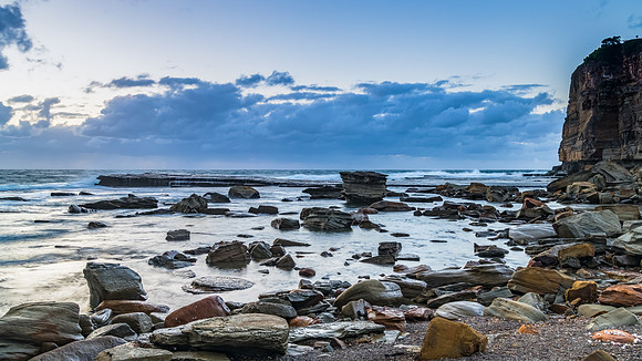 Moody sunrise seascape with clouds at the rocky inlet