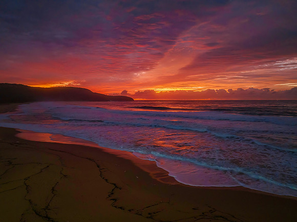 Cloud covered sunrise at the seaside in pink and blue
