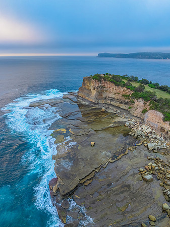 Sunrise seascape and rocky Inlet with thick fog cloud over the o