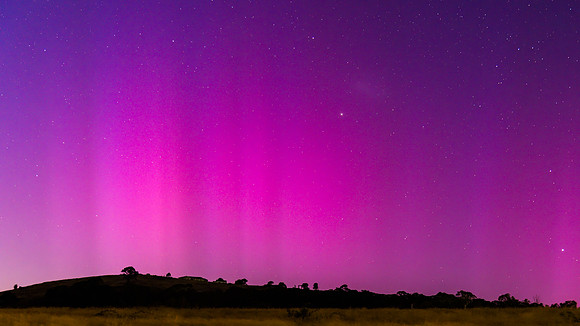 Aurora Australis display lights up the predawn sky in pinks