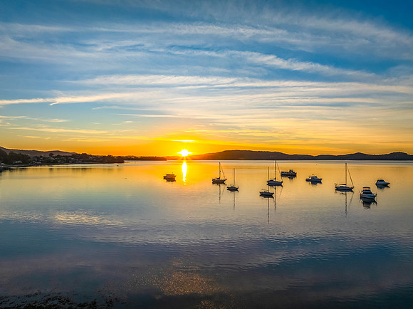 Sunrise with high cloud, boats and reflections over the water