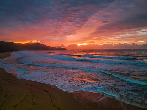 Cloud covered sunrise at the seaside in pink and blue