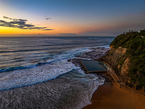 Sunrise at the beach with waves and a smattering of clouds