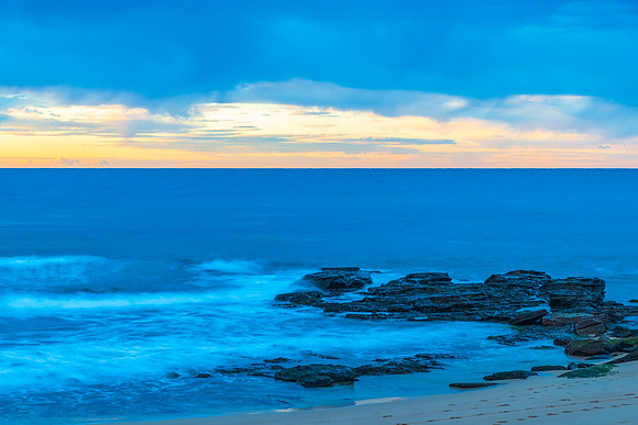 Winter sunrise by the sea shore with rain clouds