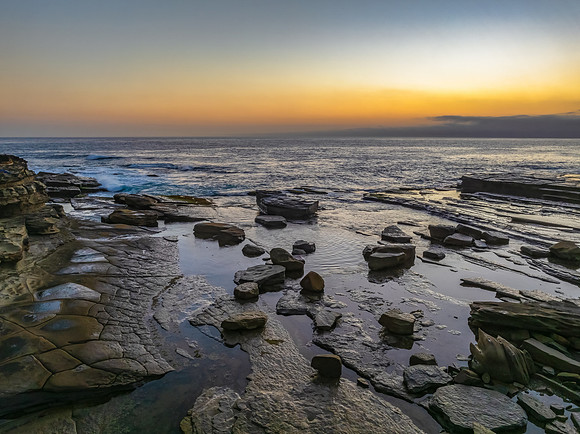 Sunrise seascape and rocky Inlet with thick fog cloud over the o