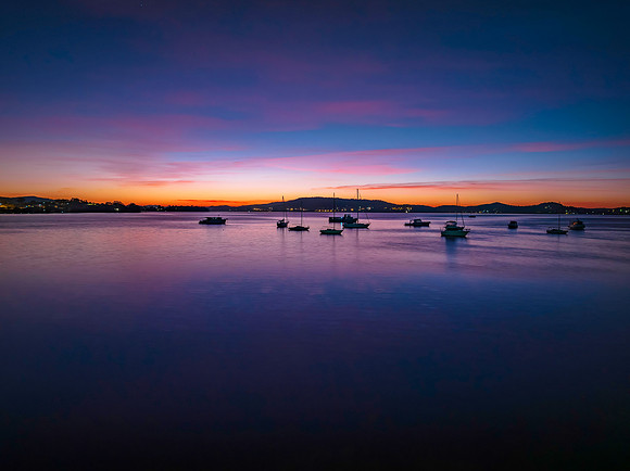 Colours of Dawn over the bay with boats and high cloud